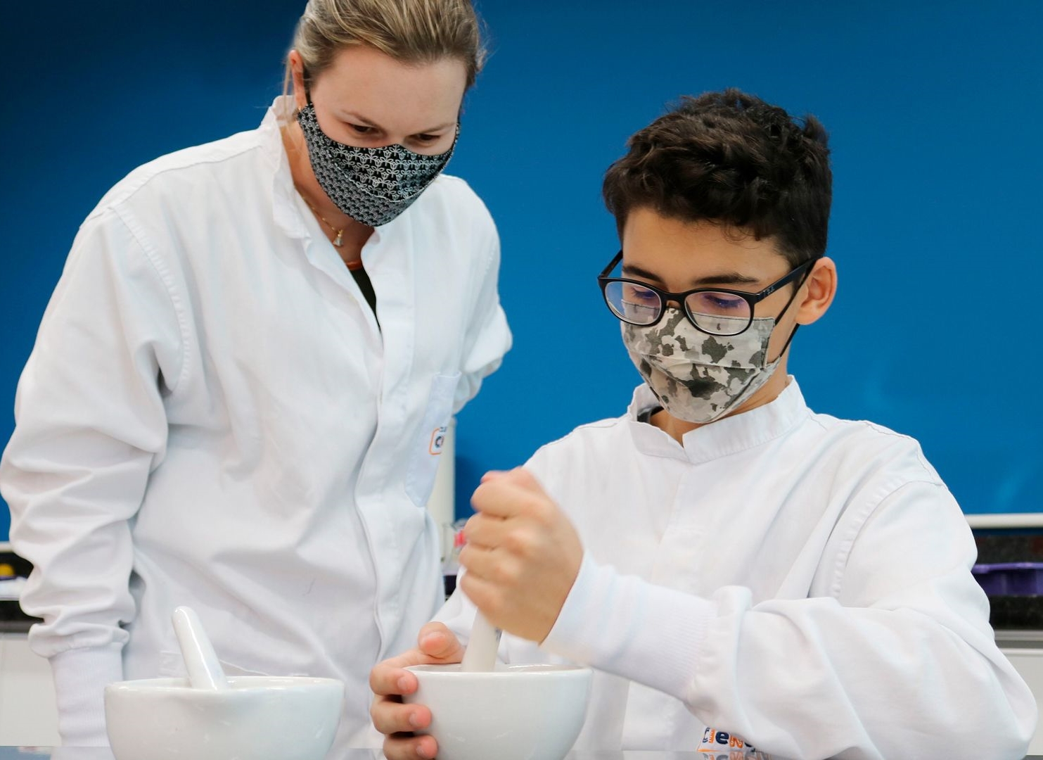 foto de professora olhando o aluno misturando algo